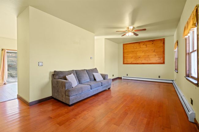 Living room featuring a ceiling fan, baseboards, a baseboard, hardwood / wood-style flooring | Image 5