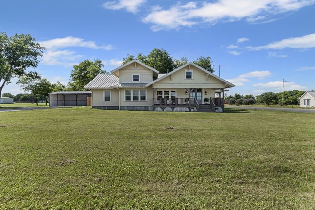 Back of property with covered porch, a lawn, and metal roof | Image 39