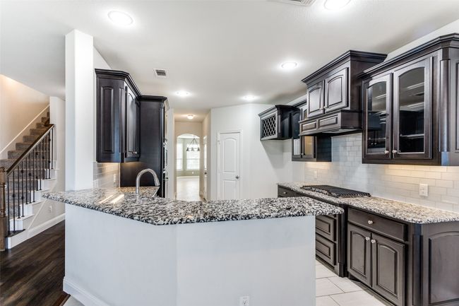 Kitchen featuring kitchen peninsula, wood-type flooring, tasteful backsplash, and stainless steel gas cooktop | Image 11