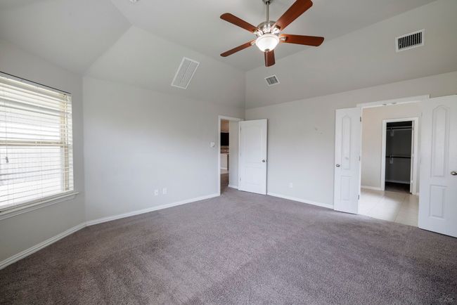 Unfurnished bedroom with carpet flooring, high vaulted ceiling, a spacious closet, and a ceiling fan | Image 11