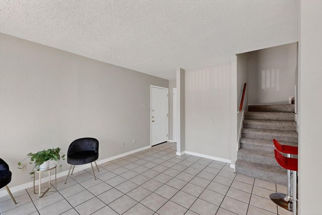 Living area featuring a textured ceiling, stairway, and light tile patterned flooring | Image 11