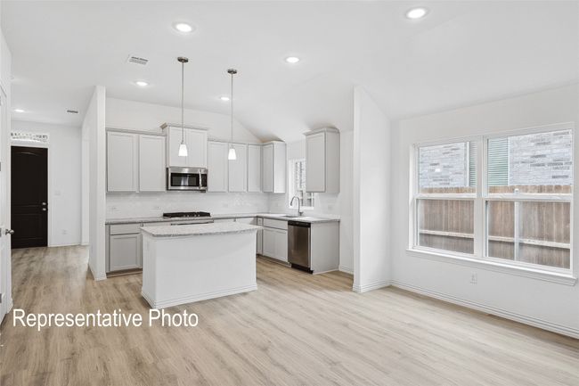 Kitchen with light wood-type flooring, stainless steel appliances, vaulted ceiling, and a center island | Image 6