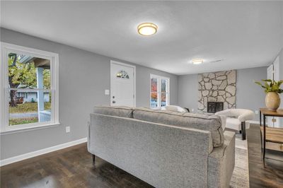 Living room with a textured ceiling, a stone fireplace, a wealth of natural light, and dark wood-type flooring | Image 2