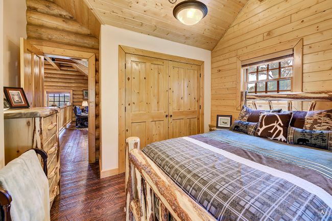 Bedroom with rustic walls, vaulted ceiling, multiple windows, parquet flooring, and wooden ceiling | Image 29