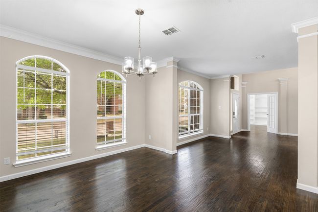Unfurnished dining area with visible vents, baseboards, ornamental molding, wood finished floors, and a notable chandelier | Image 9