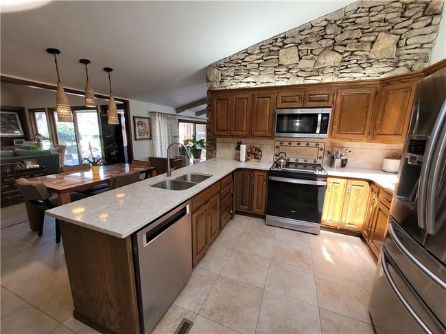 Kitchen featuring tasteful backsplash, lofted ceiling, a sink, a wealth of natural light, and appliances with stainless steel finishes | Image 17