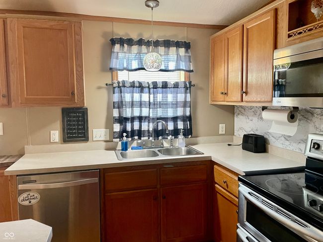 kitchen featuring stainless steel appliances, light countertops, brown cabinets, and tasteful backsplash | Image 8