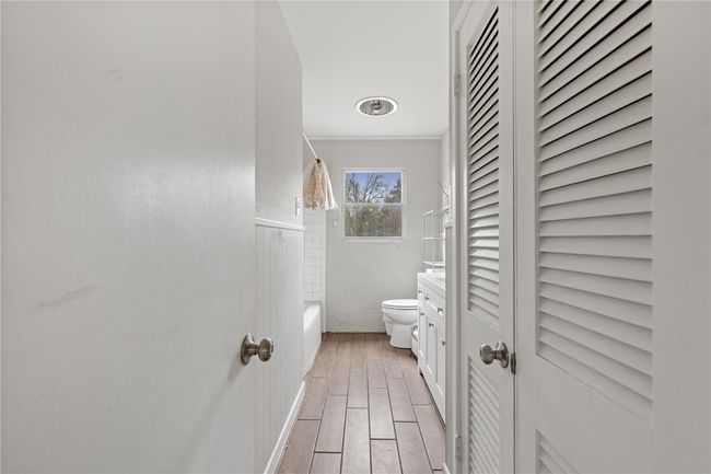Bathroom featuring bathtub / shower combination, ornamental molding, tile walls, and toilet | Image 12