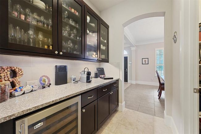 Beautiful butler's pantry with granite countertops, upper glass-front display cabinets, under-cabinet storage, and a built-in wine fridge. Perfectly situated between the kitchen and dining room for effortless entertaining and additional prep space. | Image 5