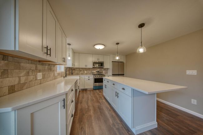 Kitchen with a sink, white cabinets, stainless steel appliances, dark wood finished floors, and backsplash | Image 9