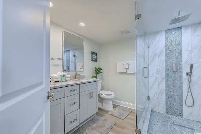 Bathroom featuring vanity, toilet, hardwood / wood-style flooring, and walk in shower | Image 26