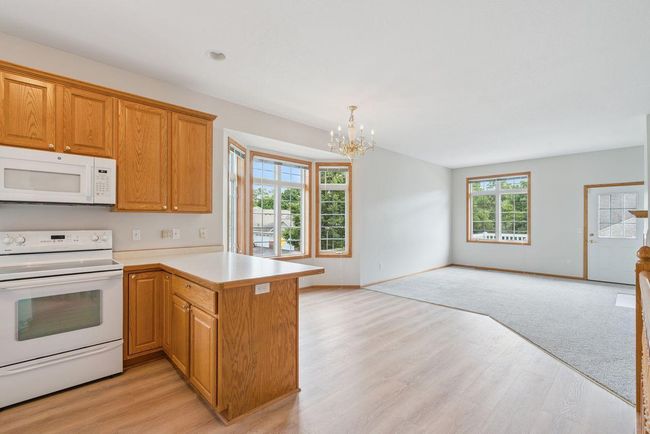 Open concept kitchen with custom 42" oak cabinets, brand new luxury vinyl plank flooring, informal dining area with bay window leading in to living room overlooking deck. | Image 5