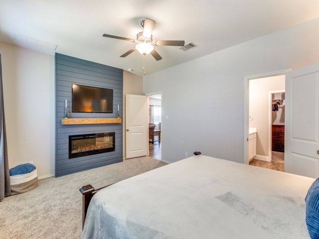 Carpeted bedroom featuring a fireplace, ensuite bath, and ceiling fan | Image 20