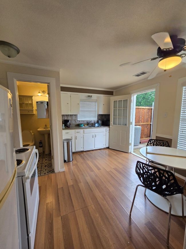 Kitchen featuring white cabinetry, backsplash, white appliances, light wood-style floors, and ceiling fan | Image 22