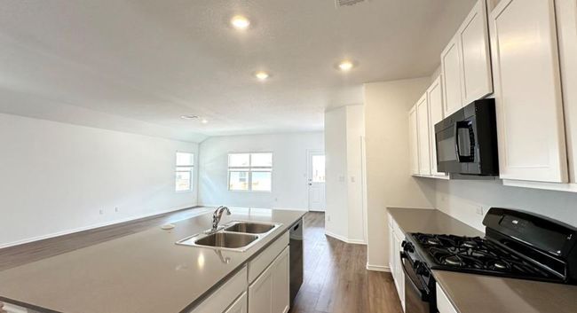 Kitchen featuring range with gas stovetop, black microwave, dark wood-type flooring, recessed lighting, and open floor plan | Image 4