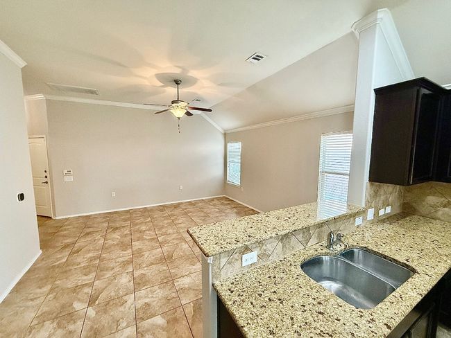Kitchen with ornamental molding, ceiling fan, light stone countertops, lofted ceiling, and dark cabinetry | Image 6
