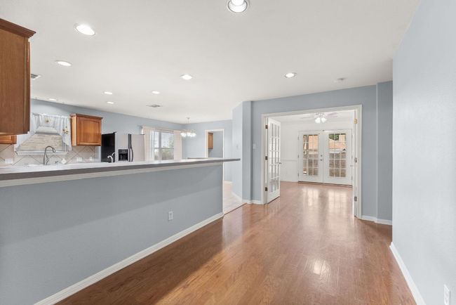 Unfurnished living room with a sink, light wood finished floors, french doors, recessed lighting, and baseboards | Image 10
