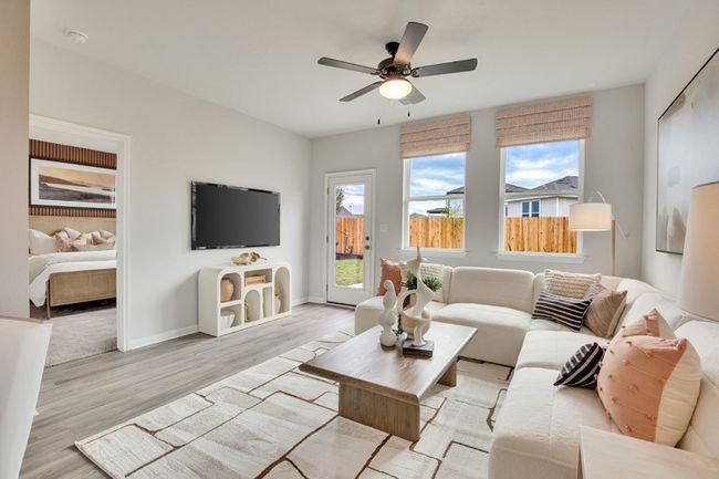Living room with light wood-type flooring, ceiling fan, and baseboards | Image 4