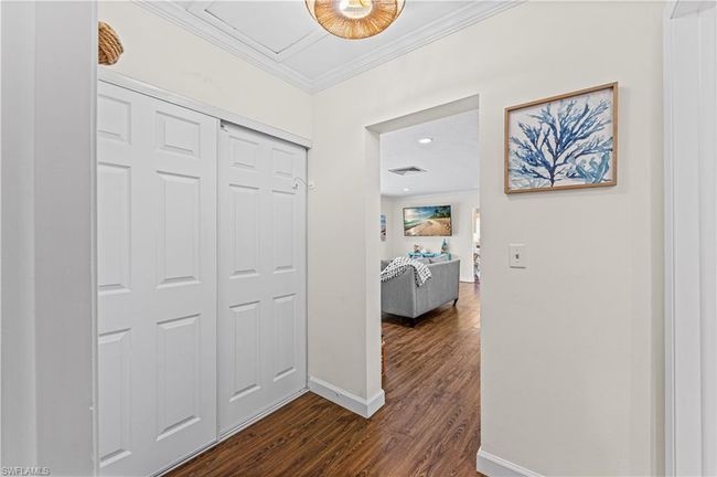 Hallway with baseboards, visible vents, dark wood-type flooring, and ornamental molding | Image 12