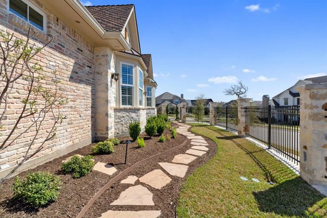 The beautiful gardenarea on the southeast side of the home features a retaining wall constructed ofcustom blend naturalstone, with a gorgeous rosegarden. The entranceon the side yard is abeautiful arched irongate and custom blend natural stonegarden/bed walls. | Image 45