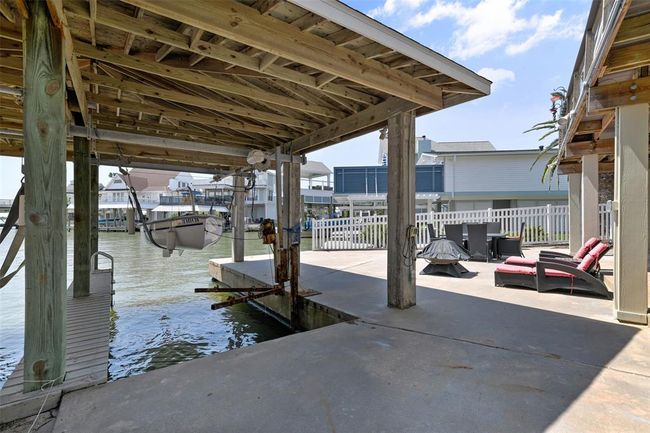Waterfront property featuring a shared boat house with lift, spacious patio area, and outdoor seating. Ideal for boating enthusiasts and outdoor relaxation. | Image 7