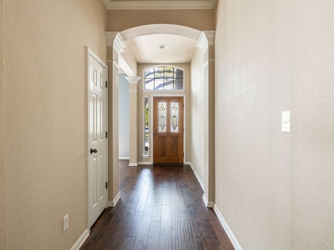 Foyer entrance featuring arched walkways, decorative columns, a textured wall, and dark wood finished floors | Image 4
