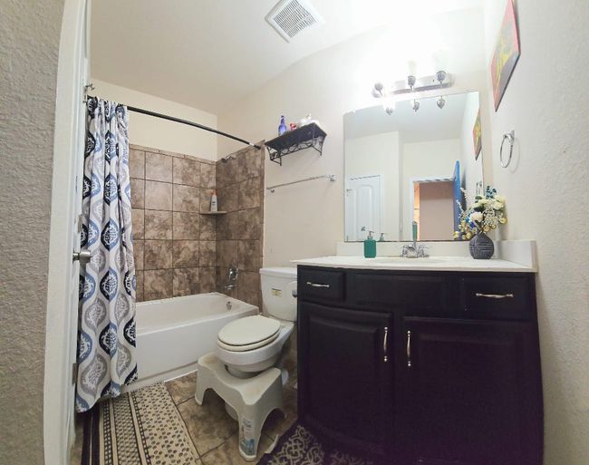 Full bathroom with vanity, shower / bath combination with curtain, and tile patterned floors | Image 17