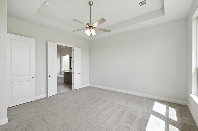 Unfurnished bedroom featuring a raised ceiling, carpet floors, and ensuite bathroom | Image 16