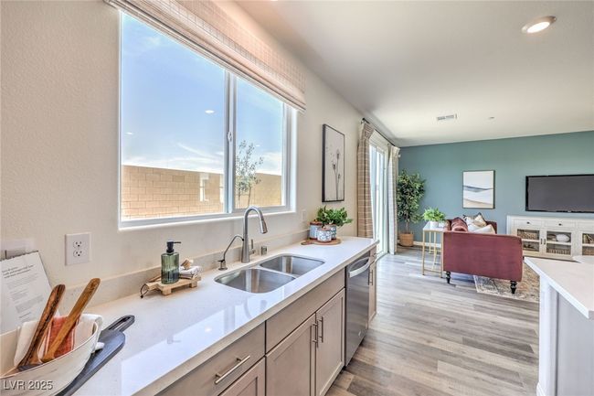 Kitchen with a sink, stainless steel dishwasher, light countertops, light. wood-type flooring, and open floor plan. Photo is representational only; actual home finishes may vary. | Image 16