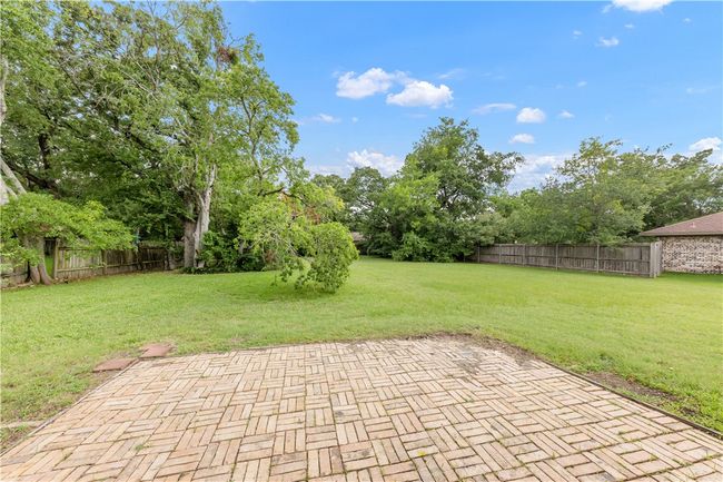 Fenced backyard with a patio and view of scattered trees | Image 18