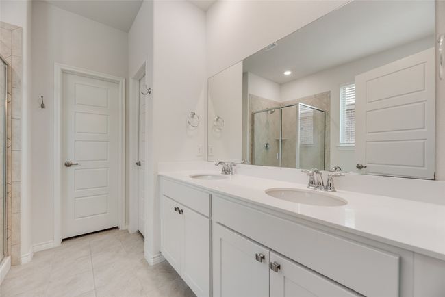 Bathroom featuring a stall shower, double vanity, tile patterned flooring, and baseboards | Image 24