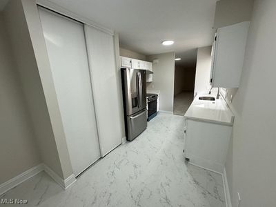 Kitchen with sink, stainless steel fridge with ice dispenser, white cabinets, and black / electric stove | Image 3