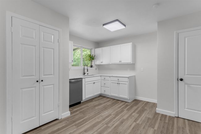 Kitchen with dishwasher, light wood-style floors, a sink, light countertops, and white cabinetry | Image 8