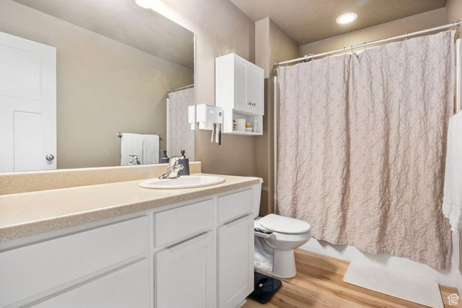 Bathroom featuring toilet, shower / bath combo with shower curtain, vanity, and wood finished floors | Image 23