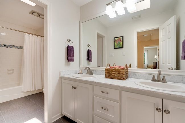Full bathroom with double vanity, shower / bath combo with shower curtain, and tile patterned flooring | Image 24