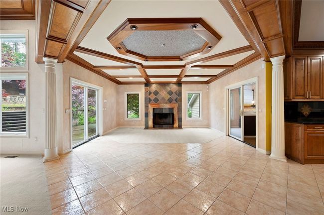 Unfurnished living room with ornate columns, coffered ceiling, crown molding, a fireplace, and beam ceiling | Image 13