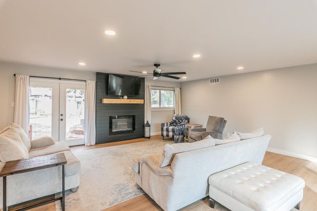 Living room featuring ceiling fan, recessed lighting, light wood-style floors, a large fireplace, and french doors | Image 7