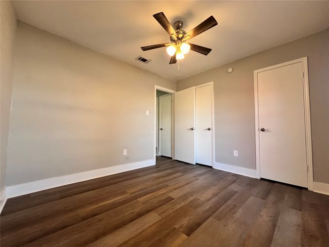 Unfurnished bedroom with ceiling fan and dark hardwood / wood-style flooring | Image 4