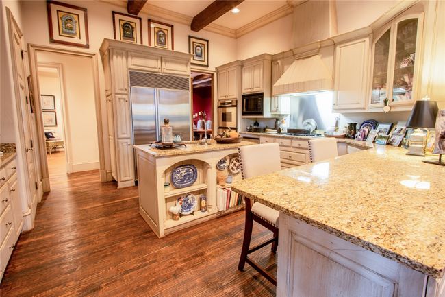 Kitchen with light stone counters, built in appliances, beamed ceiling, and dark wood finished floors | Image 5