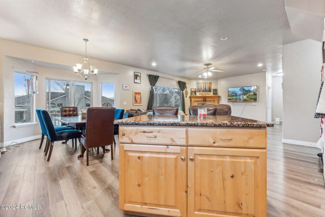 Kitchen with pendant lighting, a center island, ceiling fan with notable chandelier, light hardwood / wood-style flooring, and light brown cabinetry | Image 7