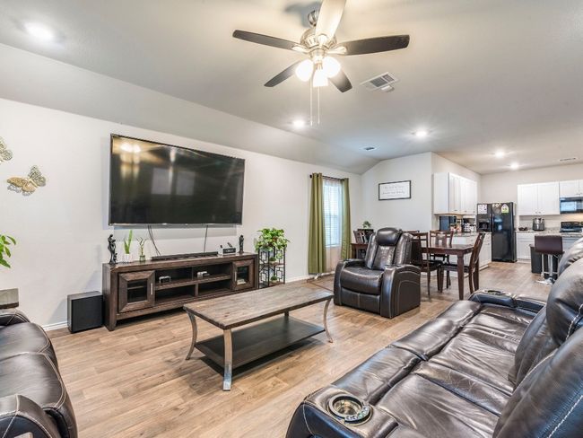 Living room featuring lofted ceiling, light wood-style flooring, baseboards, visible vents, and ceiling fan | Image 15