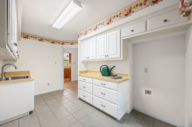 The spacious laundry room includes a utility sink, countertop for easy folding, and room for a second refrigerator. | Image 19