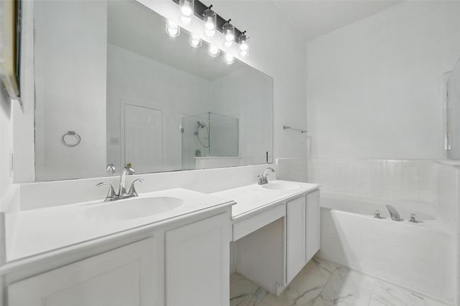 Full bathroom featuring double vanity, a bath, marble look tile flooring, and a shower with door | Image 23