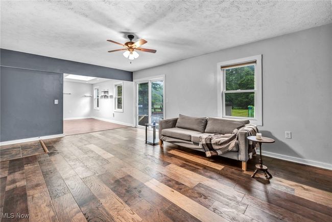 Living room featuring ceiling fan, wood finished floors, and a stone surround on a gas fireplace | Image 19