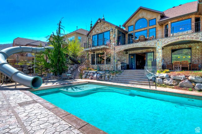 Pool featuring a patio area, a water slide, fence, and stairway | Image 4
