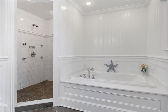 Full bathroom featuring tile patterned flooring, crown molding, a tile shower, a garden tub, and a decorative wall | Image 36