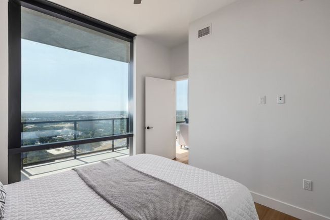 Bedroom with baseboards, wood finished floors, visible vents, and floor to ceiling windows | Image 11