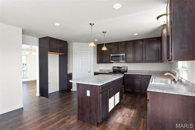 Kitchen featuring appliances with stainless steel finishes, dark brown cabinetry, a center island, dark wood-style floors, and recessed lighting | Image 8