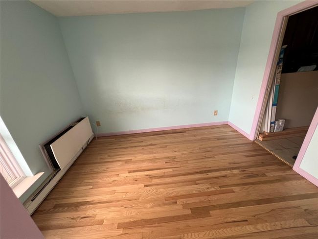 Empty room featuring light wood-style flooring, baseboards, and radiator heating unit | Image 5