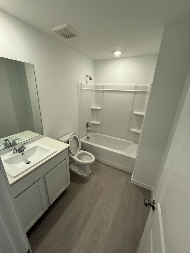 Full bath with wood finished floors, shower / bath combination, toilet, and vanity | Image 33